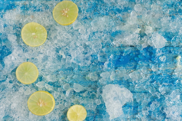 Crushed ice cubes and lemon, on vintage blue wooden table. Top view