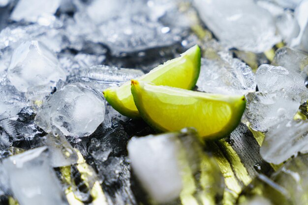 Crushed ice with lime wedges on a dark background