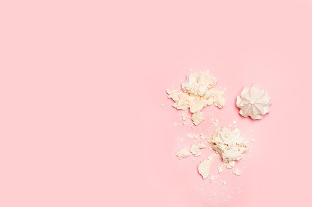 Crushed meringues on a pink background in a top view with copy space