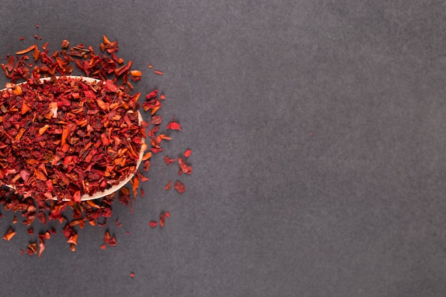 Crushed paprika in a wooden spoon, on a stone table. copyspace.