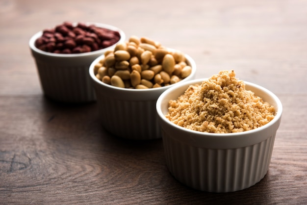 Crushed peanuts or mungfali powder with whole and roasted groundnut. Served in a bowl over moody background. Selective focus