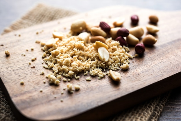 Crushed peanuts or mungfali powder with whole and roasted groundnut. Served in a bowl over moody background. Selective focus