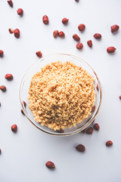 Photo crushed peanuts or mungfali powder with whole and roasted groundnut. served in a bowl over moody background. selective focus