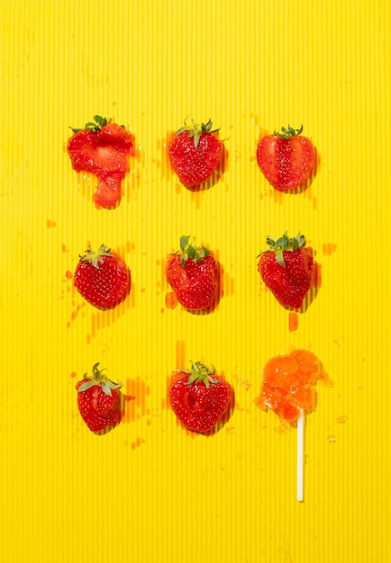 사진 노란색 배경에 분쇄 된 딸기와 릴리팝 패턴과 최소한의 여름 개념