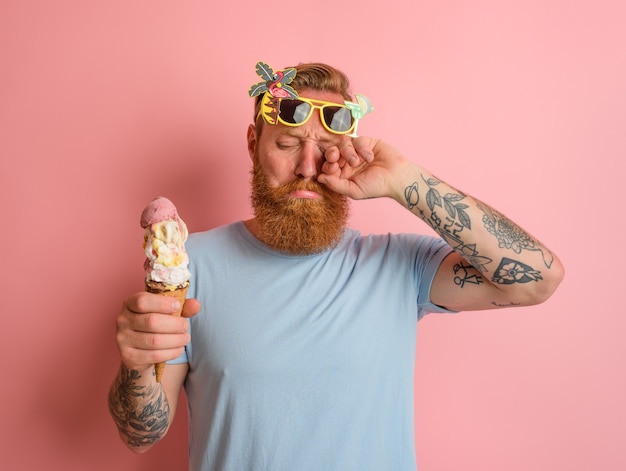 Photo cry man with beard and tattoos does not like the icecream