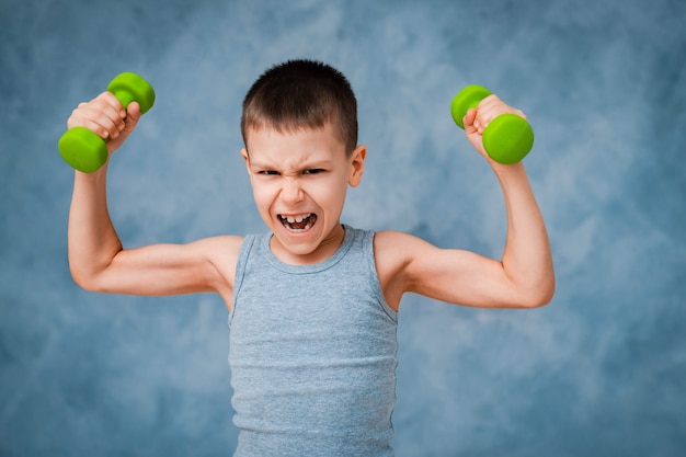 Cry sports baby boy emotionally shows his arm bicep muscle strength with dumbbells