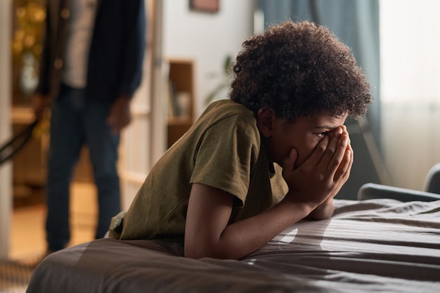 crying black boy with angry parent in background