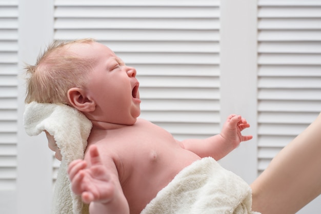 Crying blond baby without clothes. Infant colic.