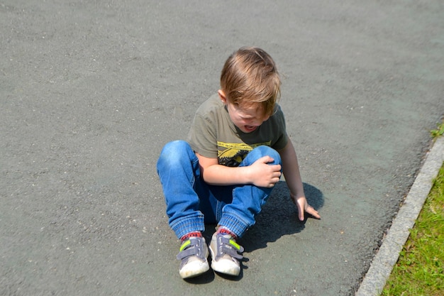 A Crying Boy on the floor in pain and holding his knee