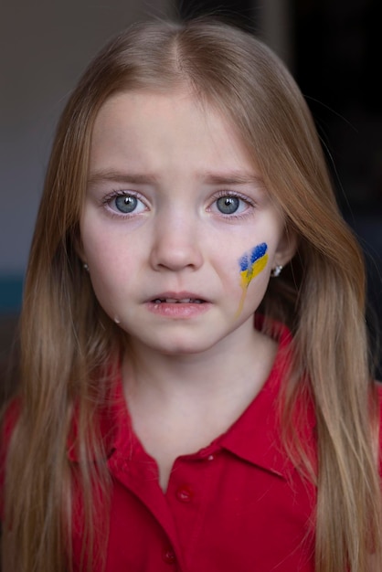 A crying child flowing tears a Ukrainian flag on her cheek children want peace