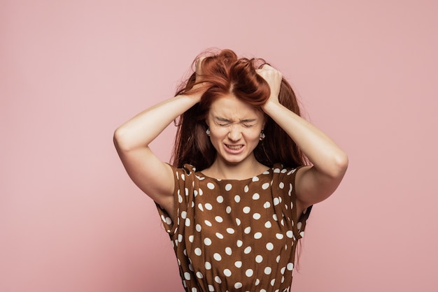 Crying emotional angry woman screaming on pink wall. Emotional, young face. Female half-length portrait