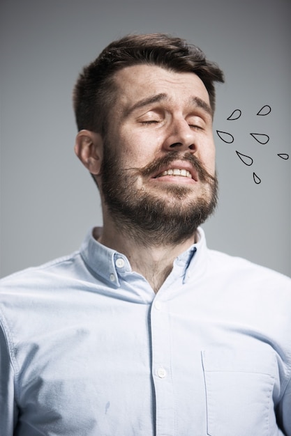 The crying man with tears on face closeup on blue wall