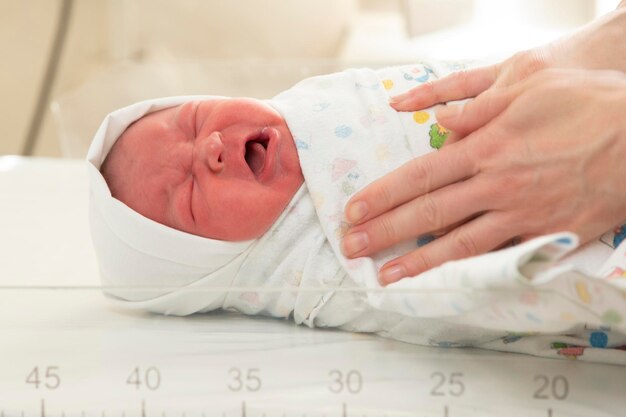 Crying newborn baby wrapped in a diaper.