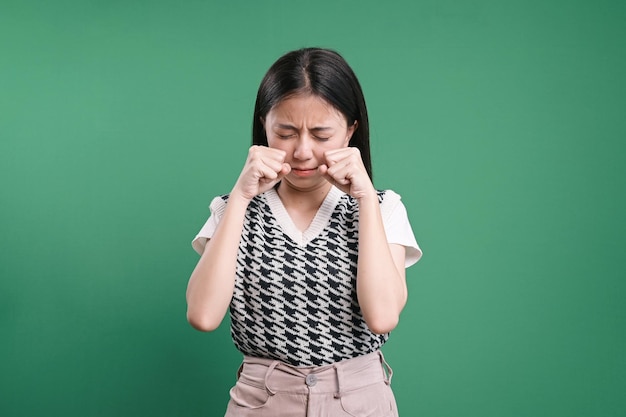 Foto giovane donna triste che piange isolata sullo sfondo verde