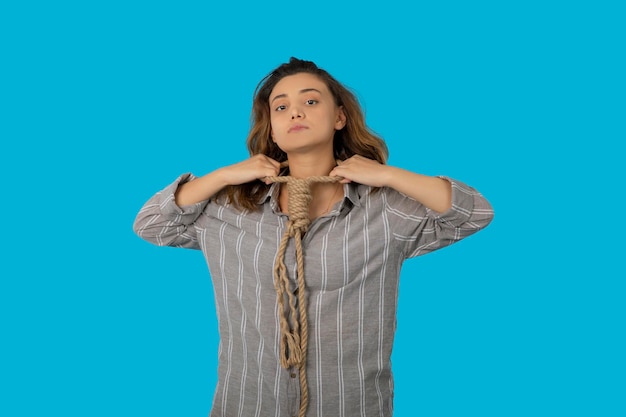 Crying young adult commits a suicide. Young girl put a rope around her neck and looking at camera. High quality photo