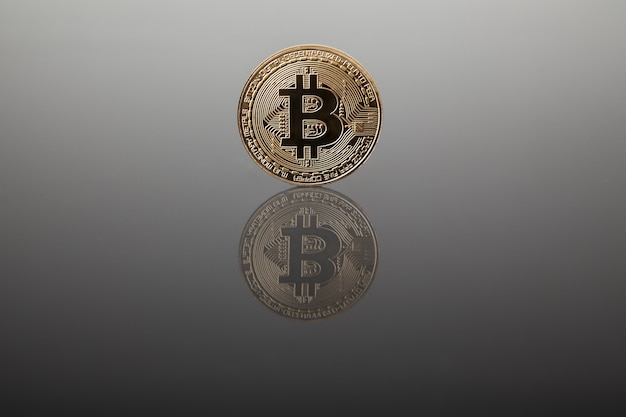 Crypto currency. Gold bitcoin on gray glass with reflection