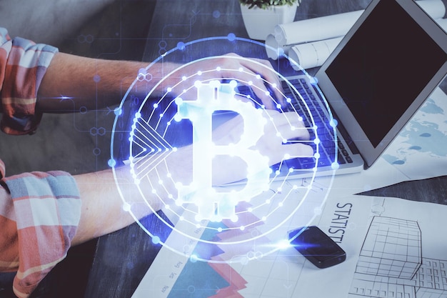 Фото Голограмма на тему криптовалюты с бизнесменом, работающим за компьютером на заднем плане. концепция блокчейна. мультиэкспозиция.