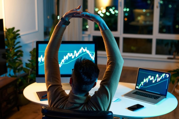 Analista dell'investitore di trader di criptovalute che guarda lo schermo del computer analizzando i dati del grafico finanziario sul monitor di pc e laptop pensando ai rischi globali del trading di borsa online, trading di investimenti.