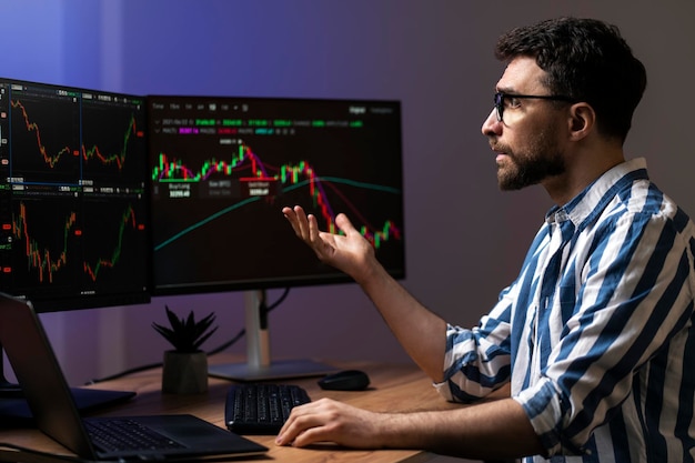 Crypto trader looking at computer monitor working online with crypto chart sitting in office