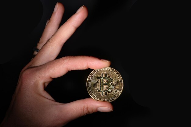 Crypto valuta Bit Coin gehouden tussen vingers op zwarte achtergrond