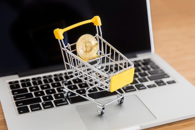 Bitcoin di criptovaluta in mini carrello del supermercato sul computer portatile