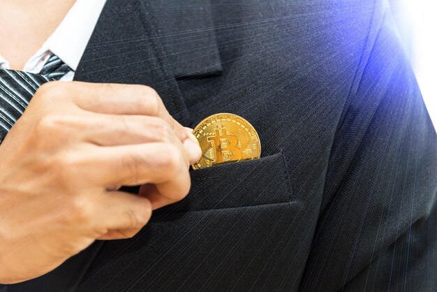 Photo cryptocurrency and business. businessman in black suite holding golden coin of btc. clodeup view wit