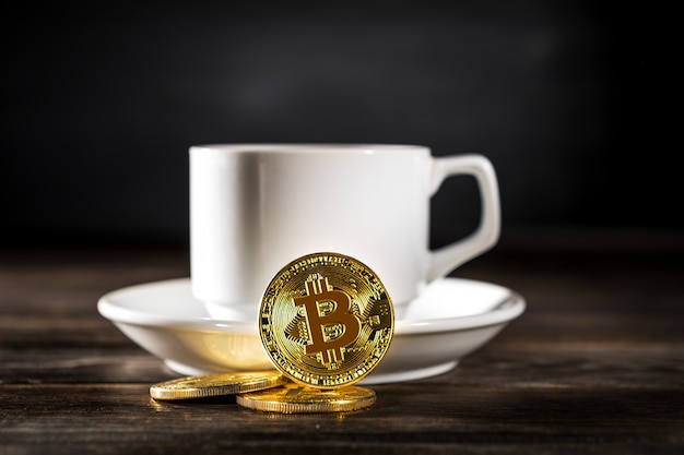 Bitcoin dorato di criptovaluta che sta sulla tazza di caffè isolata