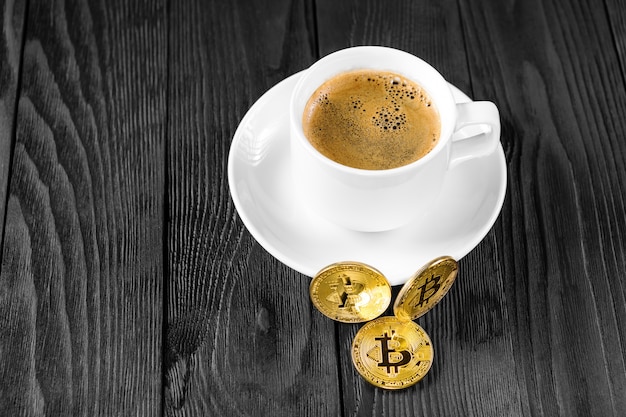 Cryptocurrency golden bitcoin standing on coffee cup 