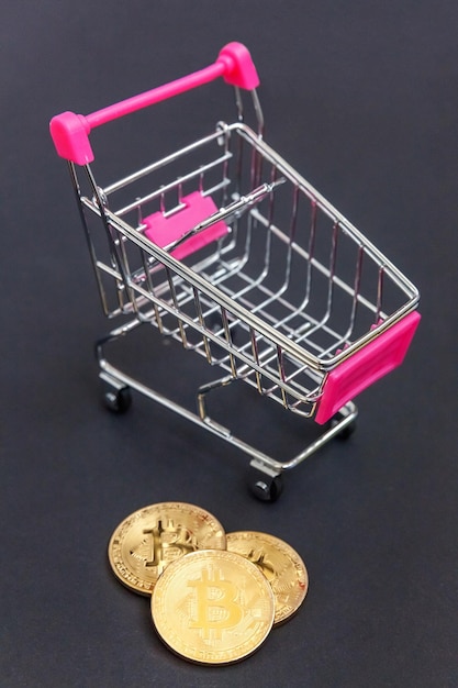Cryptocurrency gouden bitcoin munt en winkelwagentje op zwarte achtergrond Elektronisch virtueel geld voor webbankieren en internationale netwerkbetaling Symbool van crypto virtuele valuta Mijnbouwconcept