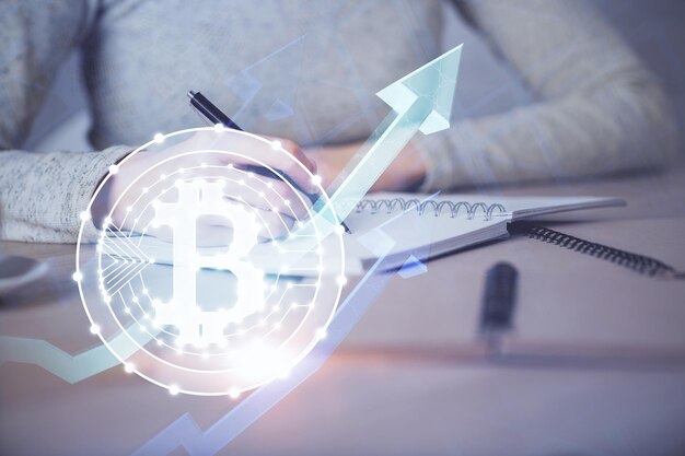 Cryptocurrency hologram over woman's hands writing background Concept of blockchain Multi exposure
