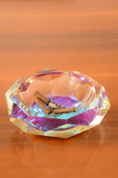 Crystal ashtray with extinct cigars on a wooden table