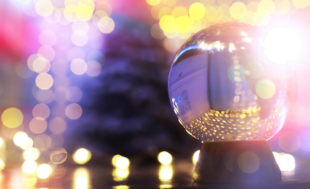 Crystal Ball on the floor with bokeh, lights behind. Glass ball with colorful bokeh light, celebration concept.