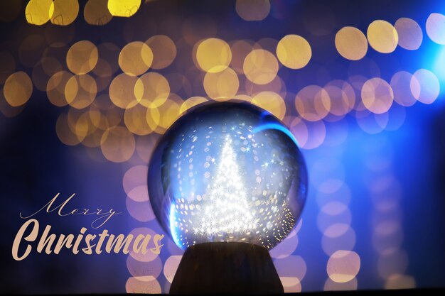 Foto sfera di cristallo sul pavimento con bokeh, luci dietro. sfera di vetro con luce colorata bokeh, concetto di celebrazione del nuovo anno.