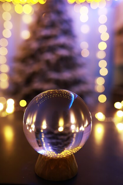 Sfera di cristallo sul pavimento con bokeh, luci dietro. sfera di vetro con luce colorata bokeh, concetto di celebrazione del nuovo anno.