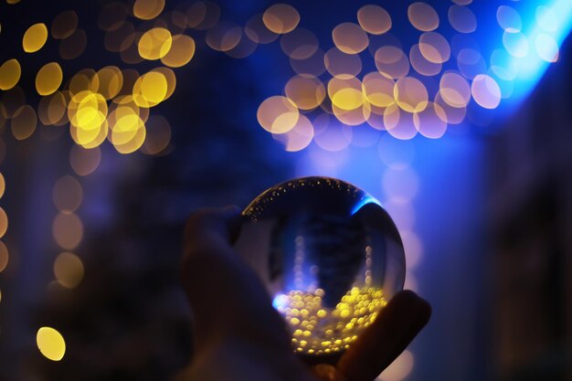 Crystal ball on the floor with bokeh, lights behind. glass ball with colorful bokeh light, new year celebration concept