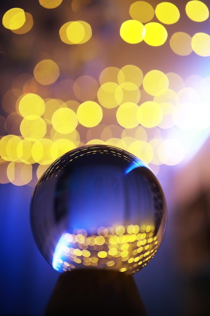 Foto sfera di cristallo sul pavimento con luci bokeh dietro sfera di vetro con luce bokeh colorata concetto di celebrazione del nuovo anno