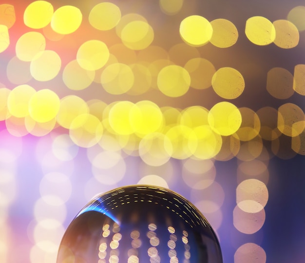 Фото Хрустальный шар на полу с боке, сзади фонари. стеклянный шар с красочным светом боке, концепция празднования.