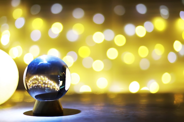 Photo crystal ball on the table with bokeh, lights behind. glass ball with colorful bokeh light, prediction concept.