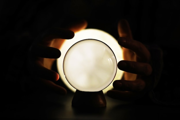 Crystal Ball on the table with bokeh, lights behind. Glass ball with colorful bokeh light, prediction concept.