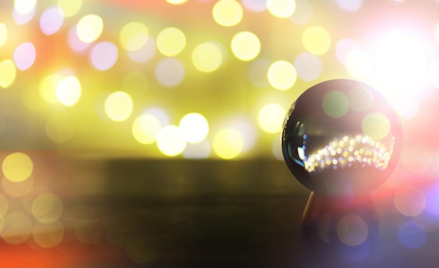 Sfera di cristallo sul tavolo con luci bokeh dietro sfera di vetro con concetto di previsione della luce bokeh colorato