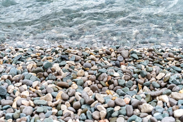 Crystal clean water washes pebbles lying on beach of sea closeup