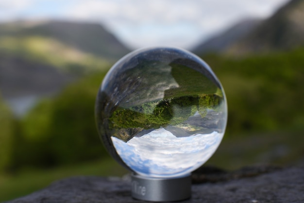 Crystal  glass ball summer landscape reflection with mountains blue sky and green trees