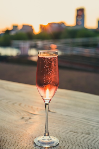 Crystal glass with pink champagne at sunset