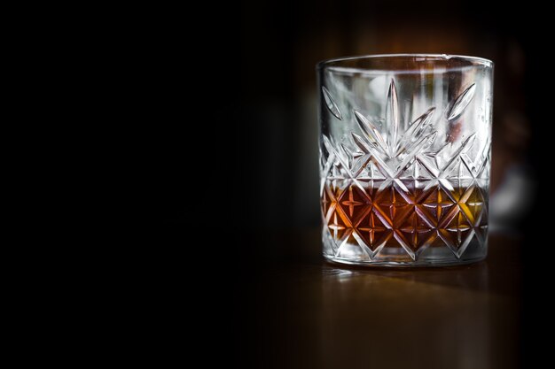 Crystal glass with whiskey, expensive alcohol, black background