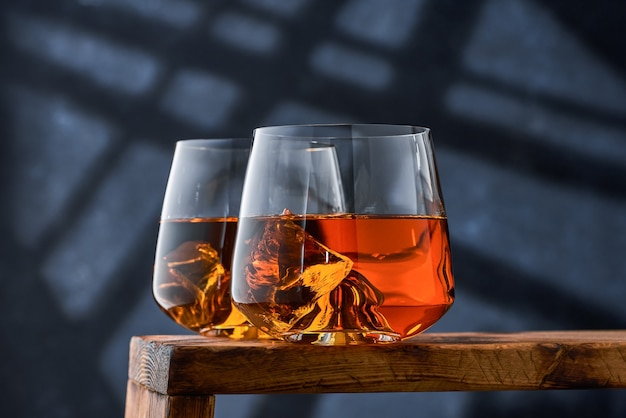 Photo crystal glasses of whiskey with ice on a wooden counter