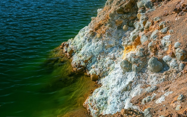 Crystals of iron sulfate and contaminated water at a shore of\
an abandoned open pit copper mine