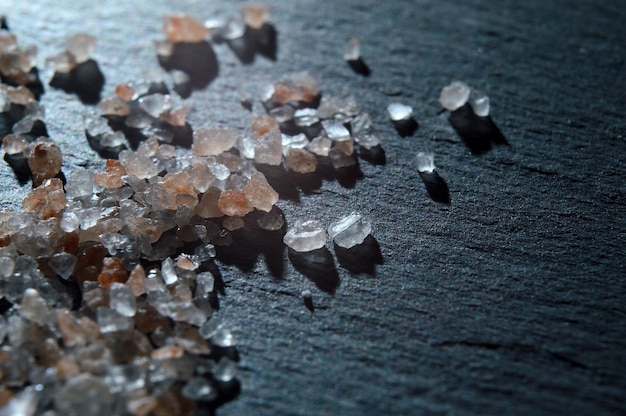 Crystals of pink salt on a black textured surface