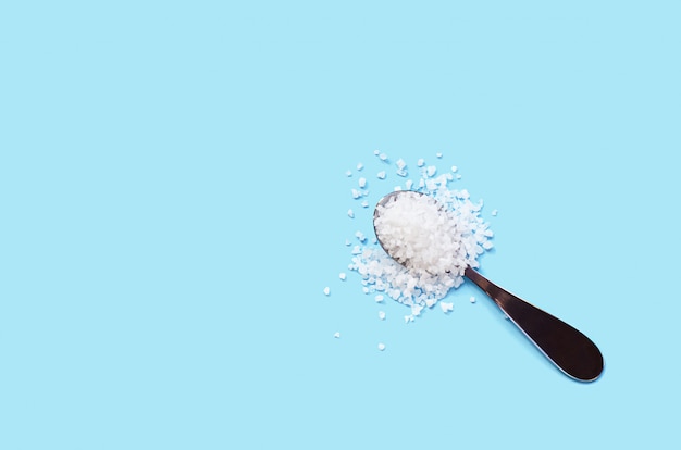 Crystals of sea salt in spoon on blue