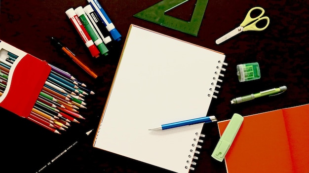 Photo cuaderno de dibujo, utiles escolares, fondo negro, lapices de colores, espacio creativo, ideas