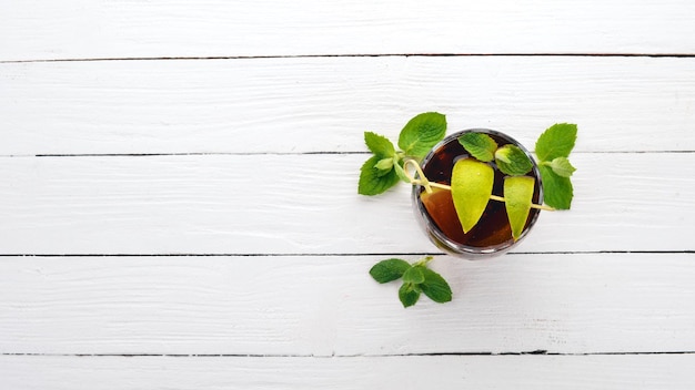 Cuba libre cocktailglas Lime mint Op een witte houten achtergrond Vrije ruimte voor tekst